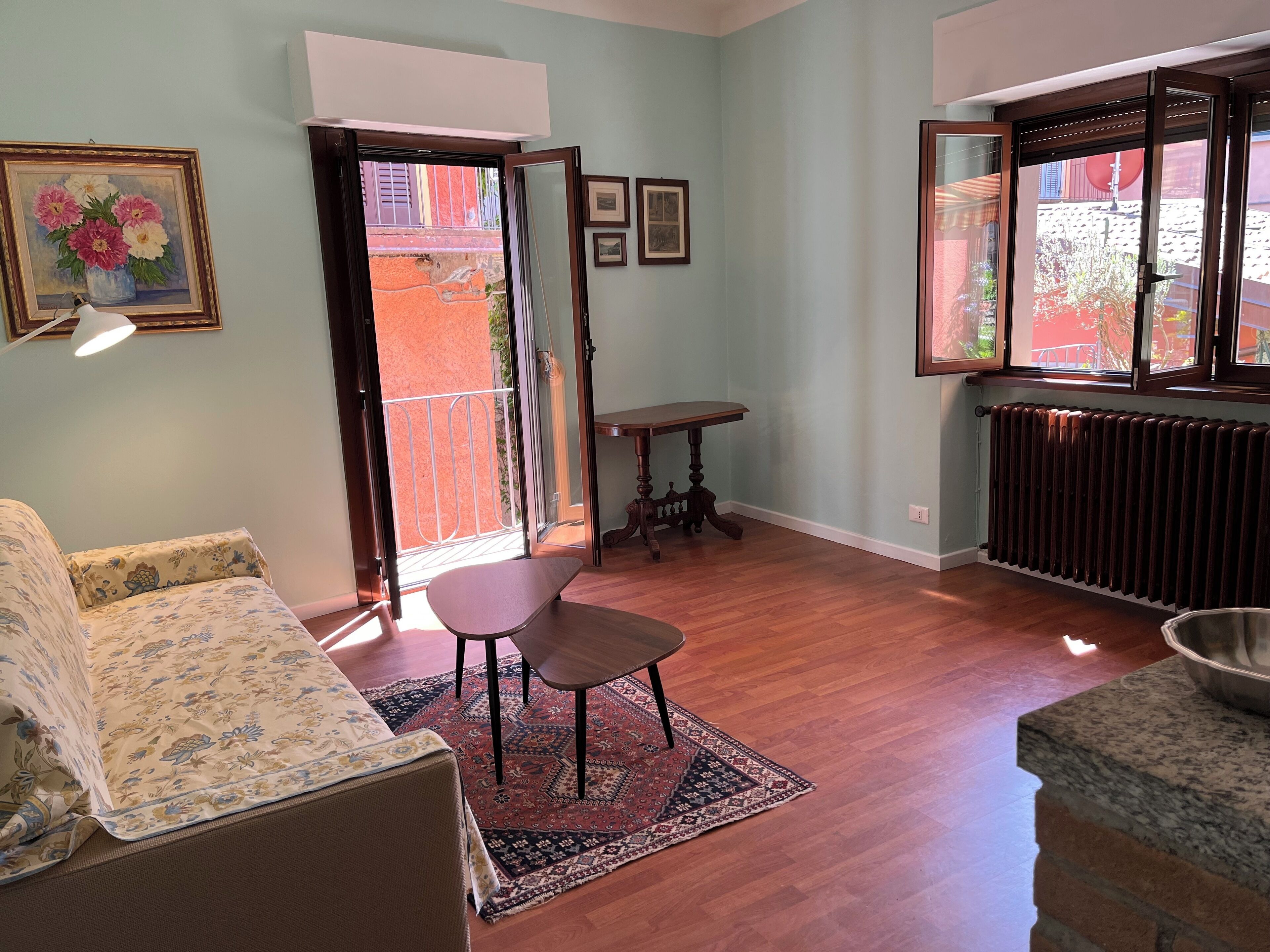 Una sala de estar con sofá, una mesita y una silla. Hay una puerta que da a un espacio exterior.