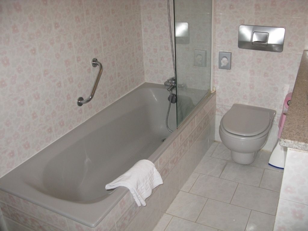 A bathroom with a bathtub, a toilet, and a glass shower enclosure.