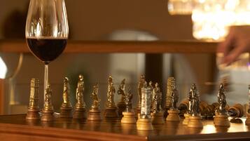 A chessboard with chess pieces and a glass of red wine on a wooden surface.