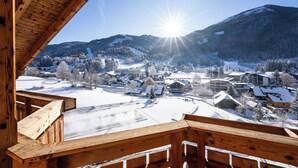 A wooden balcony overlooking a snowy village with a mountain backdrop. - Thermenwelt Hotel Pulverer (Bad Kleinkirchheim)