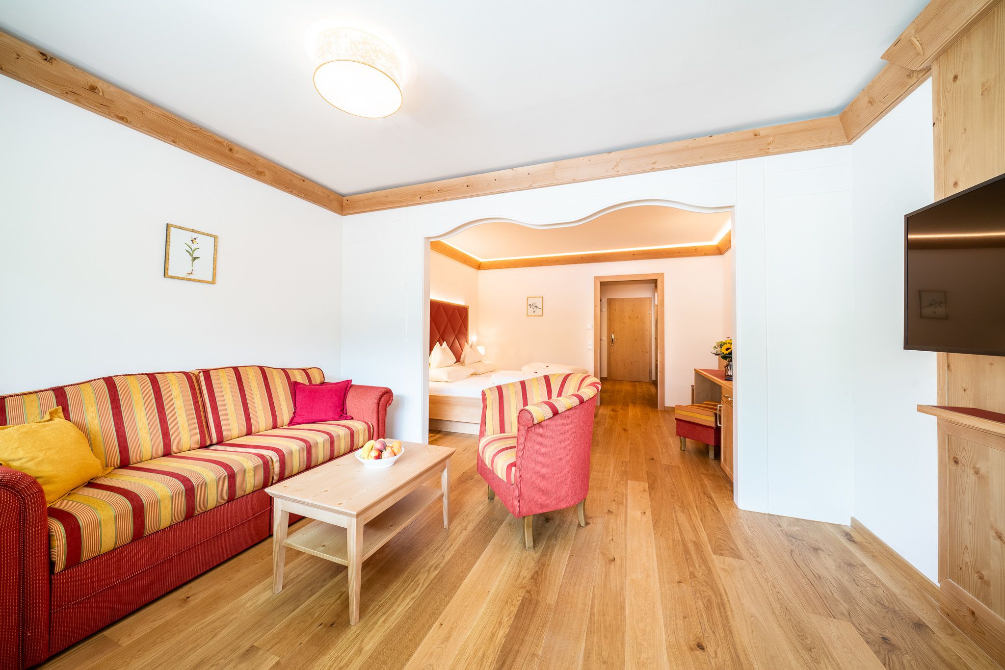 Ein Wohnzimmer mit einem gestreiften Sofa, einem kleinen Tisch und einem roten Sessel.
