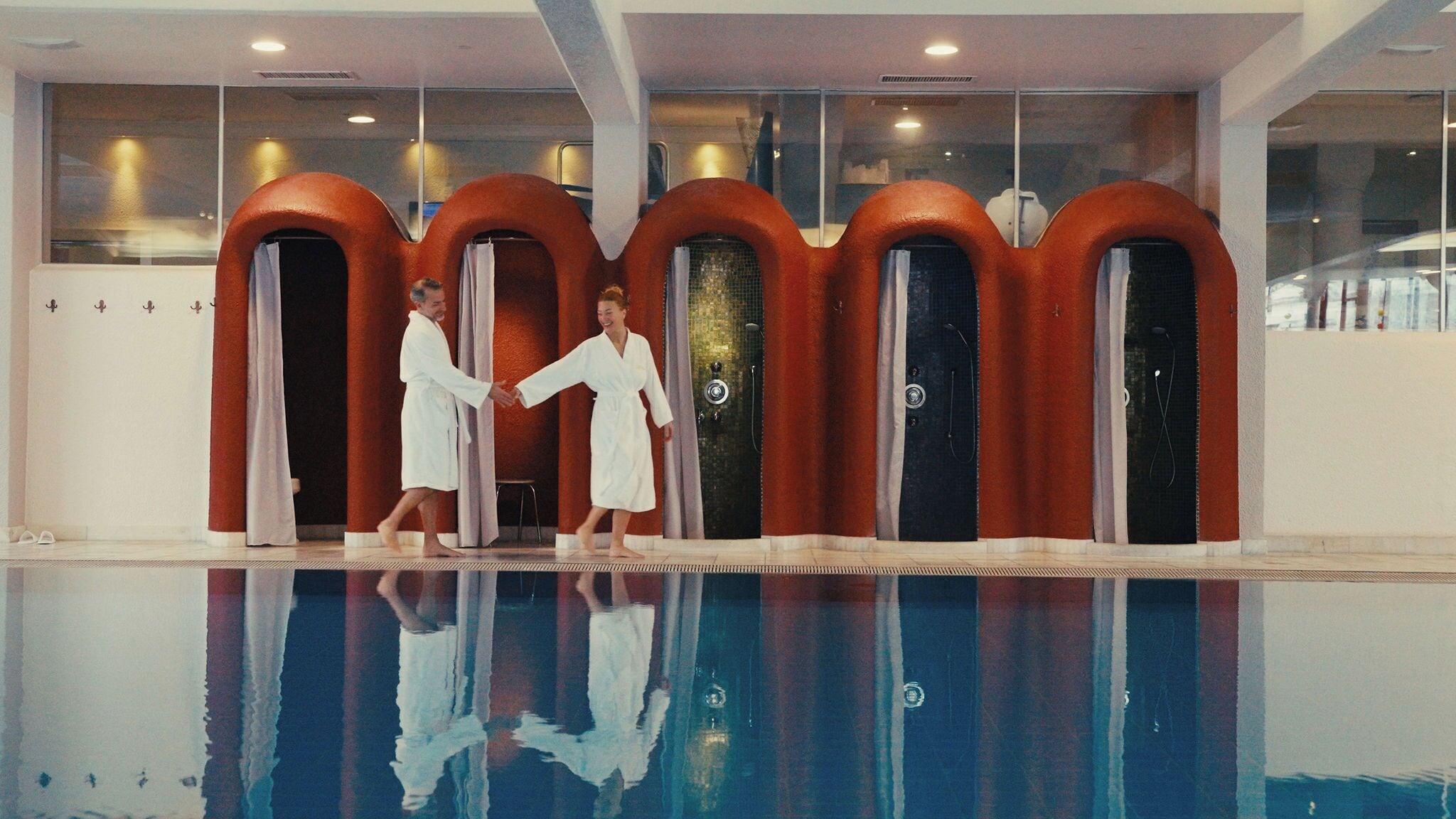 A swimming pool with a reflection of two people in white robes.