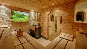 A sauna room with wooden walls, a stone wall with a scenic view, and wooden benches. - Thermenwelt Hotel Pulverer (Bad Kleinkirchheim)