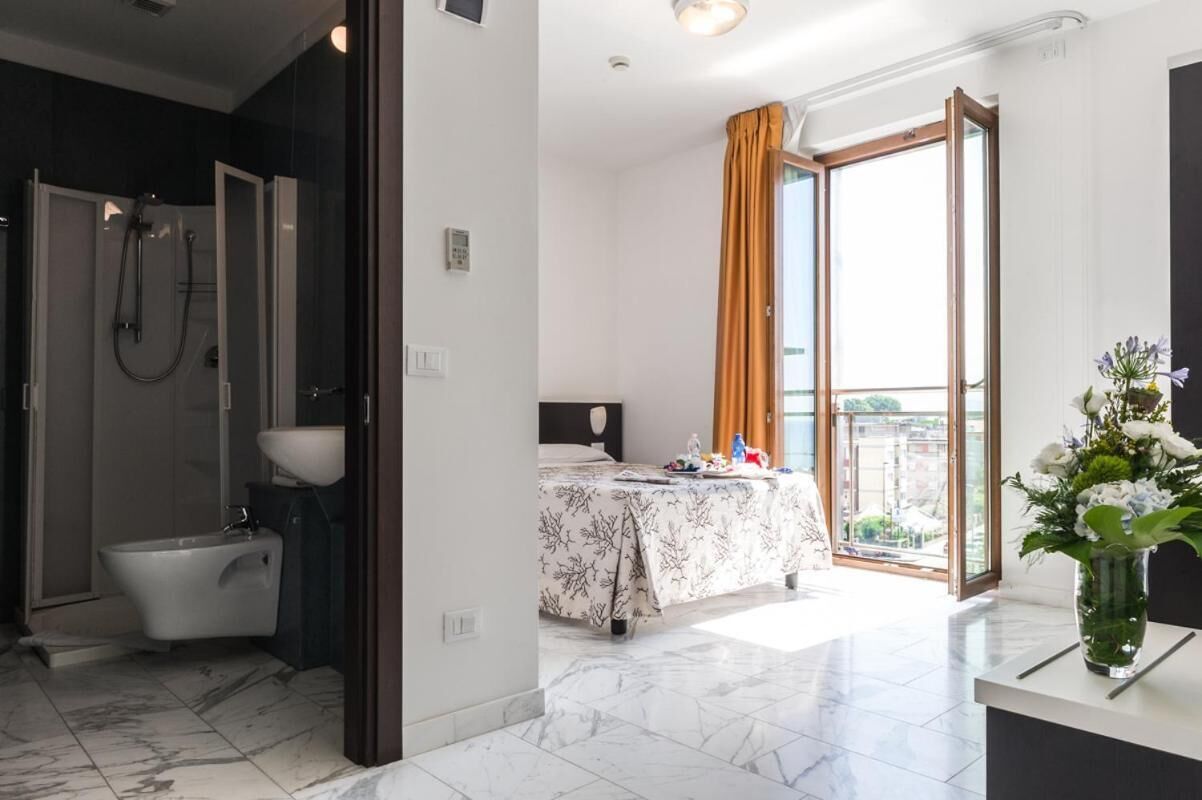 A modern hotel room with a shower, toilet, and bed.
