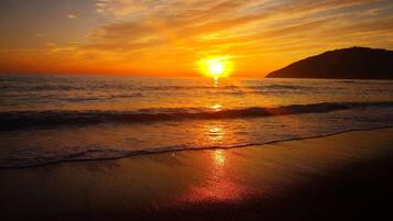 A sunset over the ocean with waves on the shore.