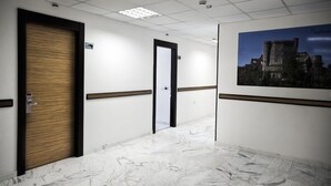 Un pasillo con suelo de mármol, puertas de madera y un cuadro en la pared.