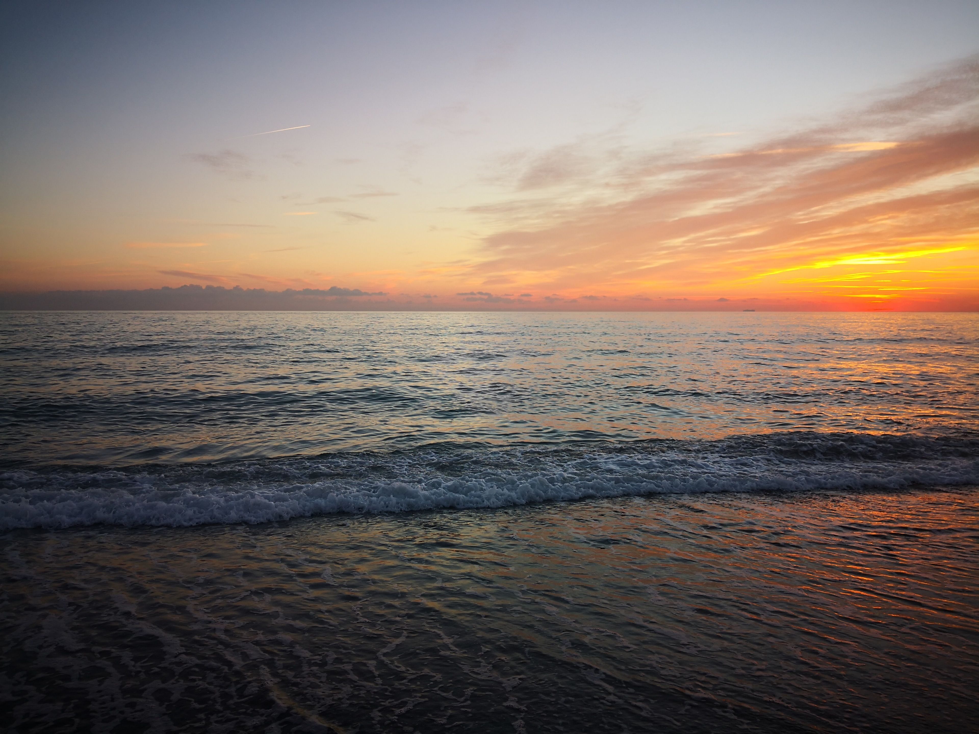A beach with waves at sunset.