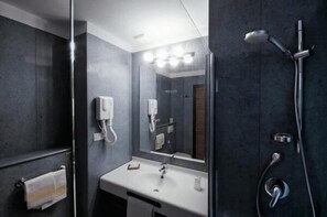 A modern bathroom with a white sink, a large mirror, and a shower with a handheld showerhead. - Hotel Rondine (Sarzana)