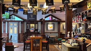 Un pub con mobiliario de madera, una zona de bar y un letrero que dice