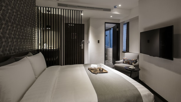 Une chambre d’hôtel moderne dotée d’un grand lit, d’une télévision, d’un coin salon et offrant une vue sur la ville.