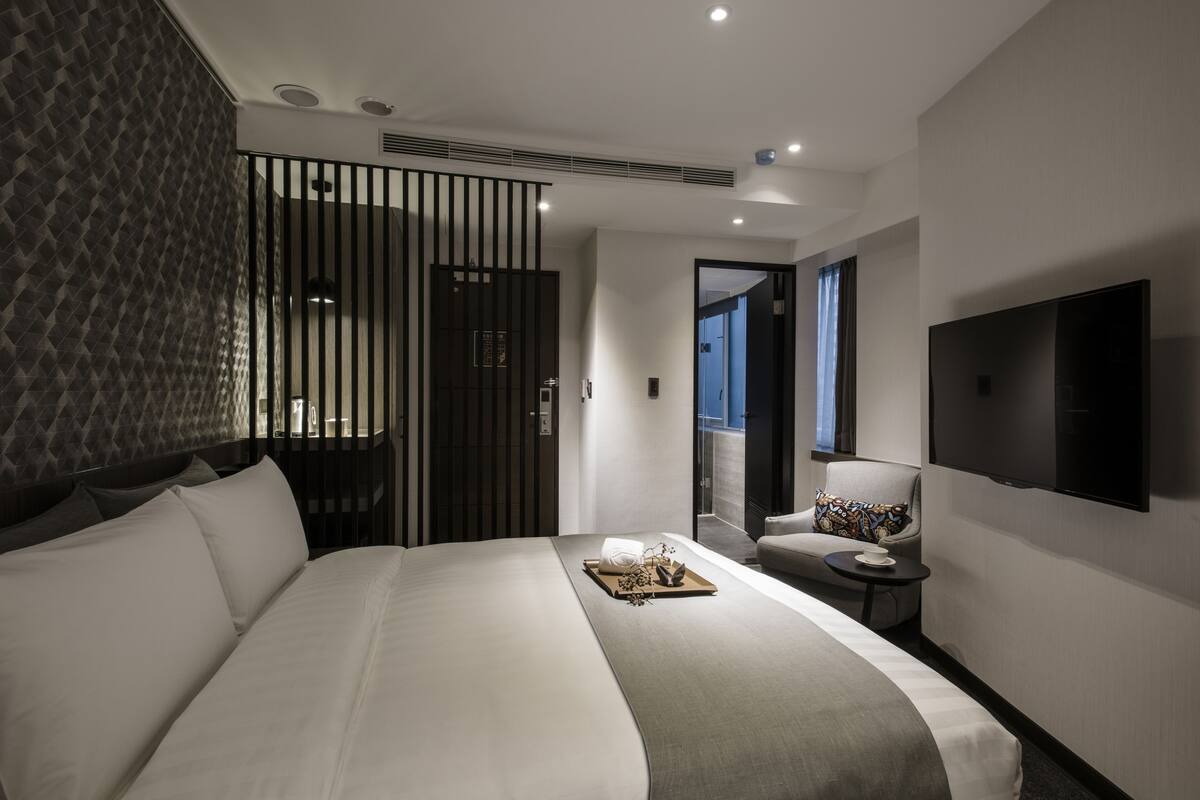 Une chambre d’hôtel moderne dotée d’un grand lit, d’une télévision, d’un coin salon et offrant une vue sur la ville.