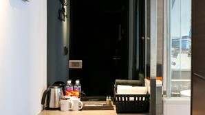 Une chambre d’hôtel compacte, dotée d’une kitchenette, d’une petite poubelle et d’une fenêtre donnant sur un paysage agréable.