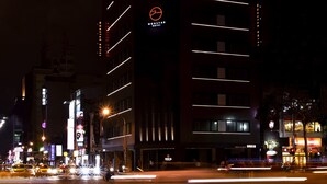Un hôtel moderne, doté d’un logo bien visible, de plusieurs étages et de fenêtres illuminées.