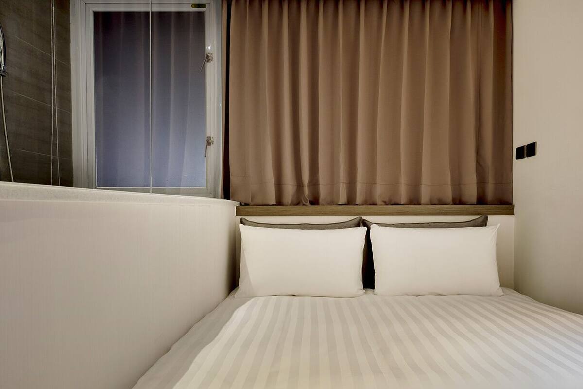Une chambre d’hôtel avec un lit, une fenêtre avec des rideaux et une porte.