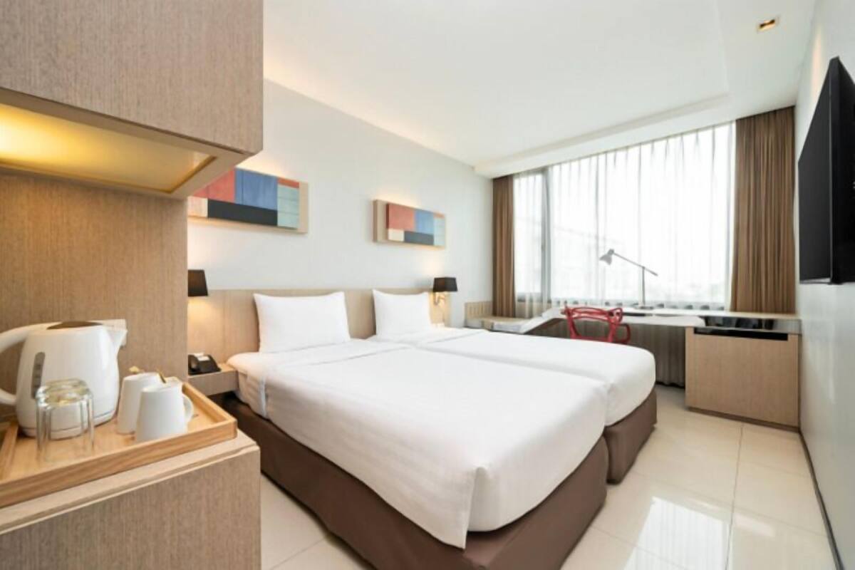A modern hotel room with a large bed, a desk, and a TV.