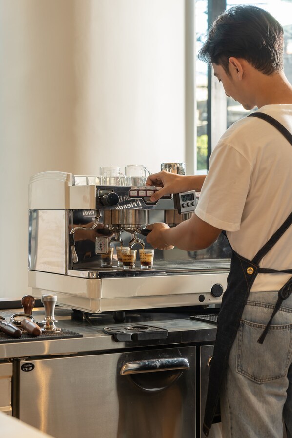 A barista at work, preparing a drink with a coffee machine.