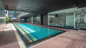 Ein moderner Innenpool mit Glaswänden, einem Holzboden und Blick auf das umgebende Gebäude.