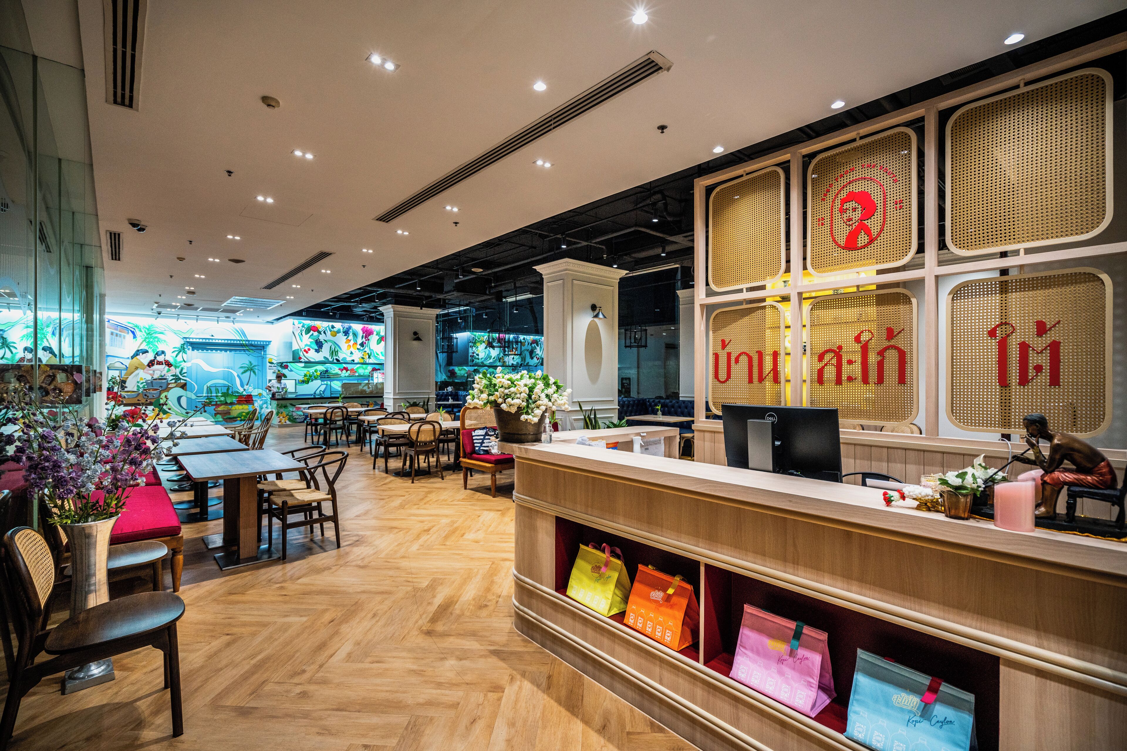 A restaurant interior with wooden flooring, a reception desk, and a seating area with tables and chairs.