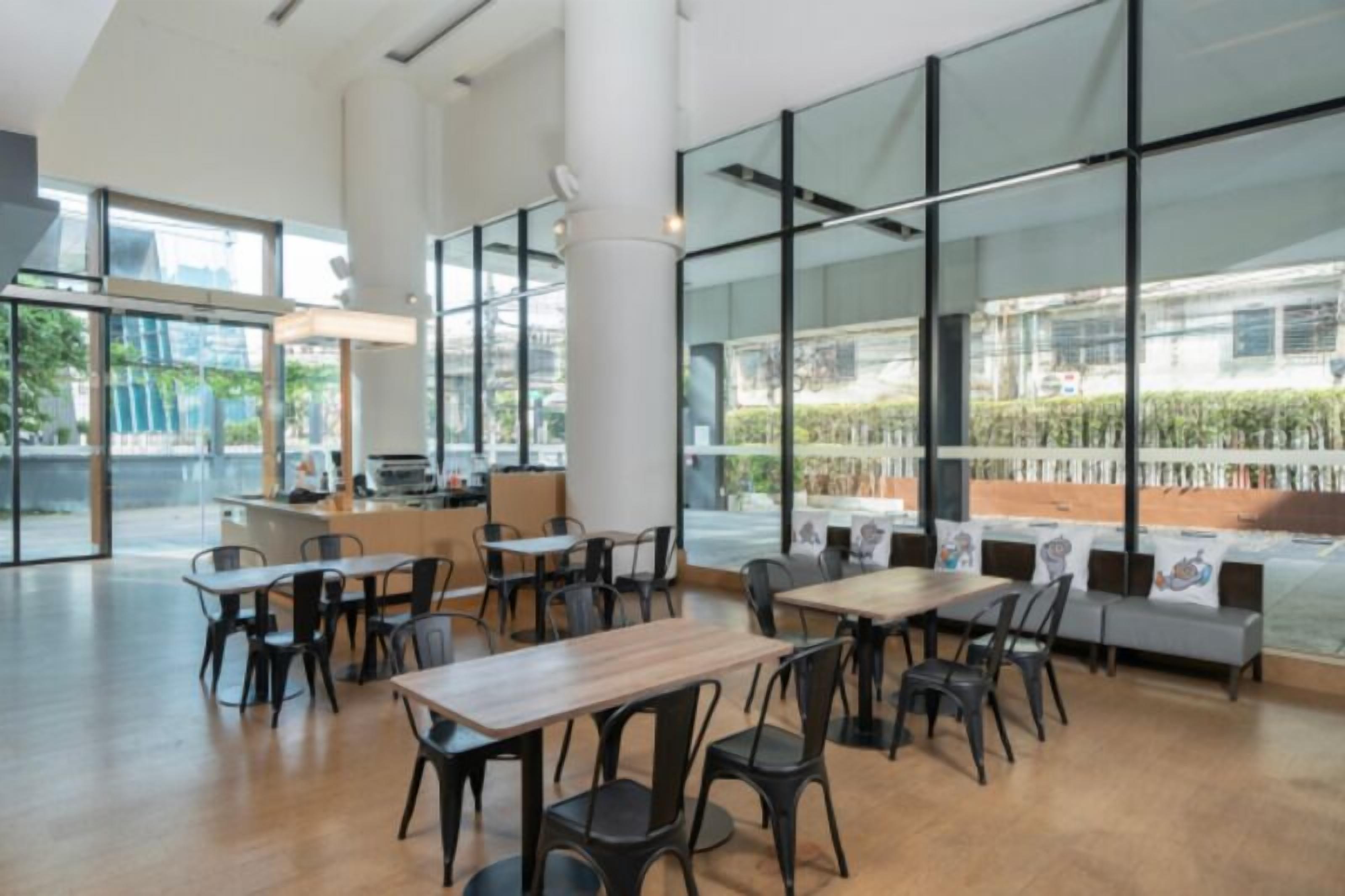 A spacious indoor area with large windows, tables, chairs, and a counter.