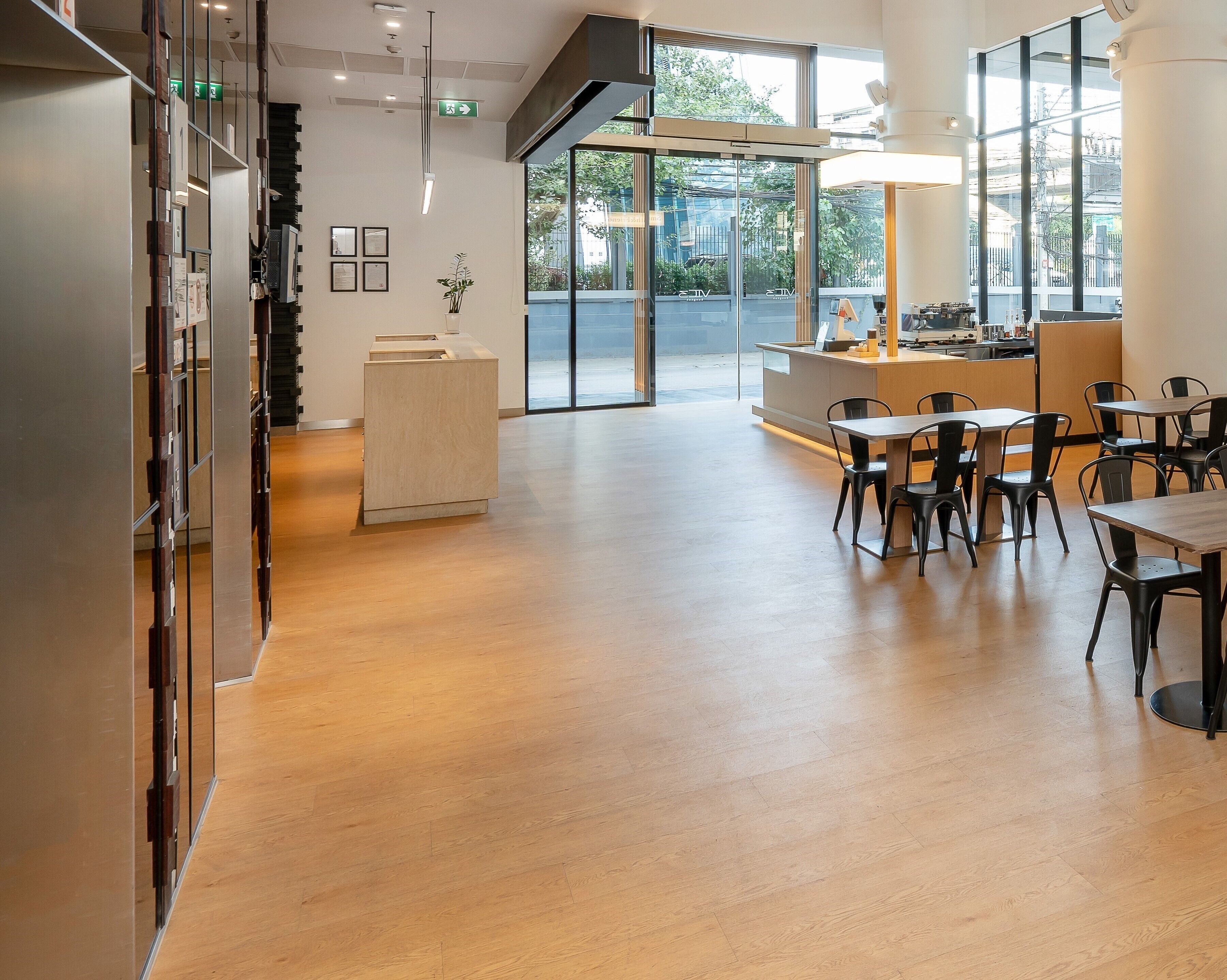 A modern hotel lobby with a reception desk, seating area, and large windows offering a view of the street.