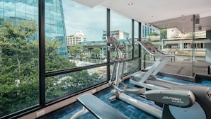 Ein Fitnessstudio mit Laufband, Ellipsentrainer und Bank, großen Fenstern mit Stadtblick und einem modernen architektonischen Design.