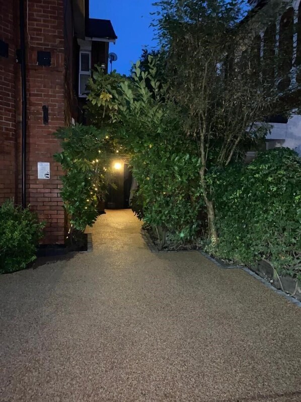 A pathway leading to a building with a brick facade and a satellite dish.