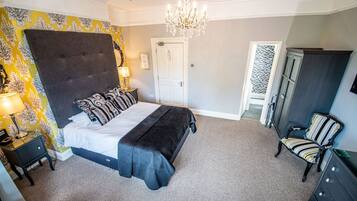 A bedroom with a large bed, a chandelier, a chair, and a wardrobe.
