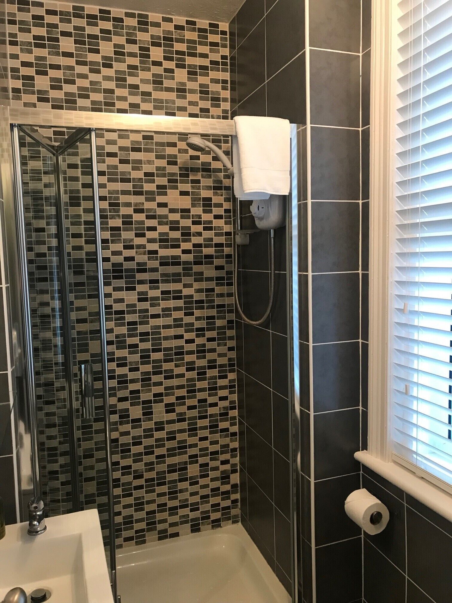 Un baño con cabina de ducha de vidrio, un lavamanos blanco y un inodoro.