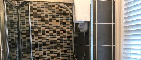 Un baño con cabina de ducha de vidrio, un lavamanos blanco y un inodoro.