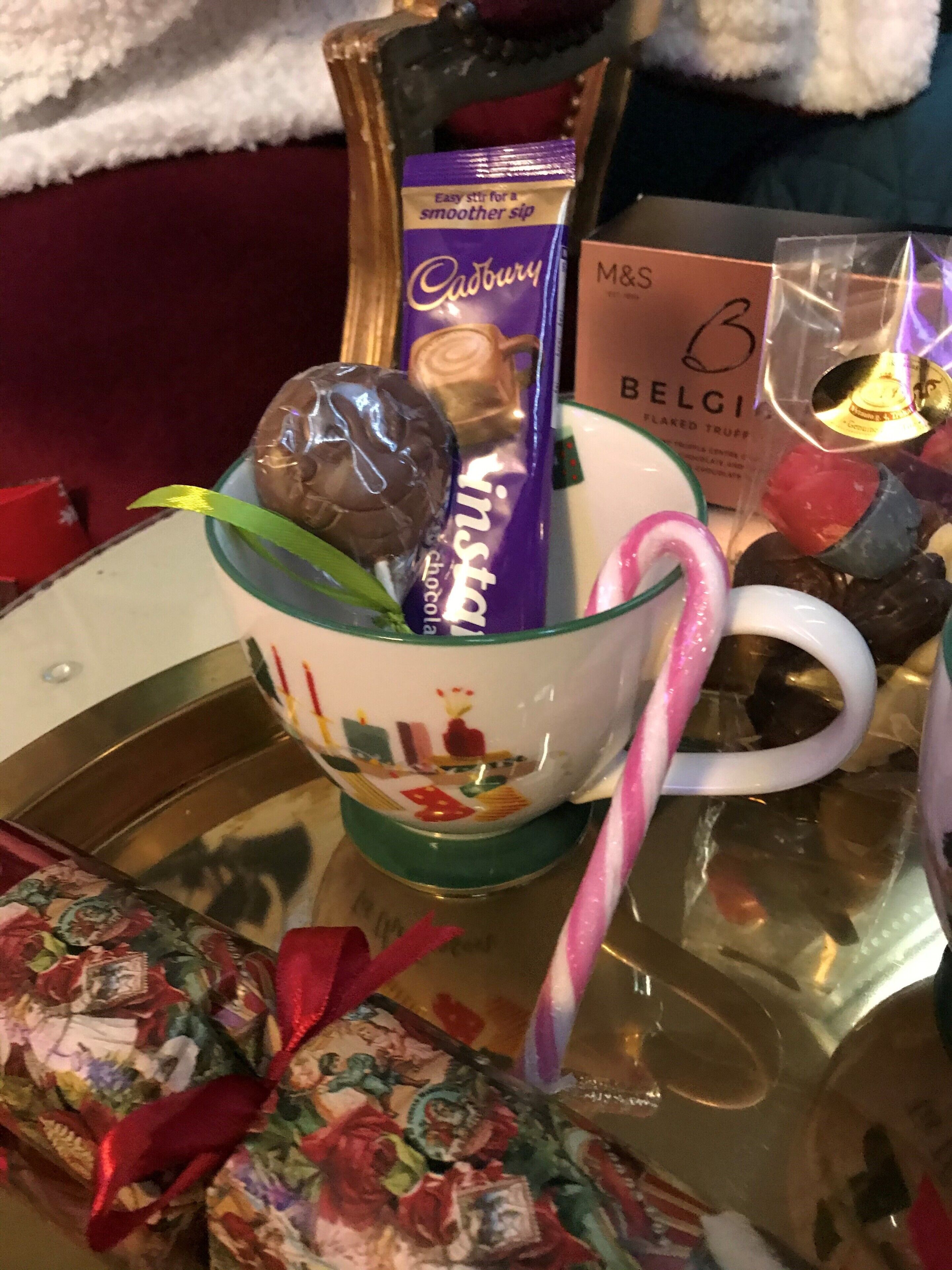 A glass mug with a festive design, a Cadbury chocolate bar, and a candy cane.