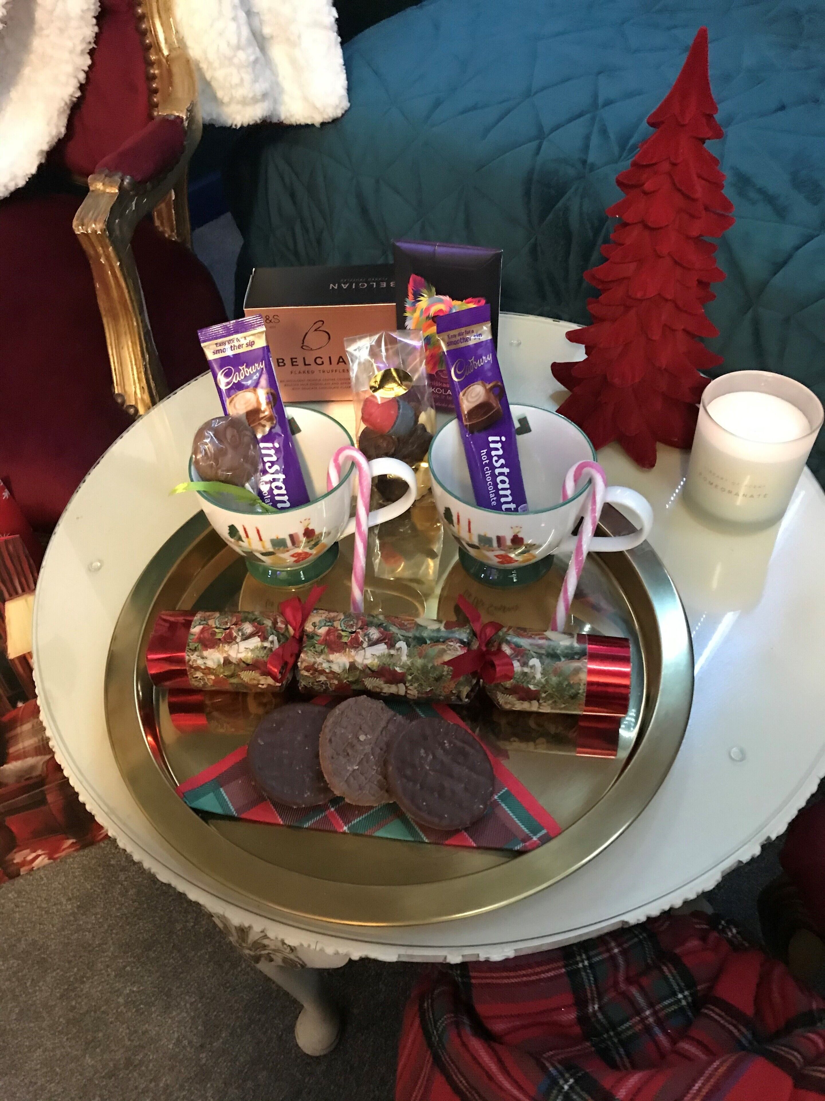 A festive table setting with chocolate treats, a candle, and a Christmas tree.
