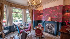 A dining area with a fireplace, patterned wallpaper, and a chandelier. - Amarillo (Bournemouth)
