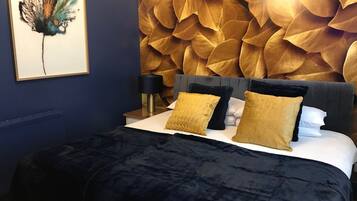 A bedroom with a bed, a nightstand, a lamp, and a wall art piece.