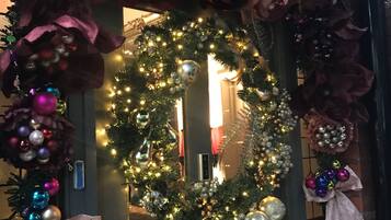 Eine Haustür, geschmückt mit einem Weihnachtskranz, Lichterketten und weihnachtlichen Verzierungen.