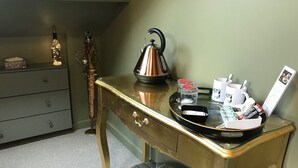 A room with a gold-colored desk, a kettle, a tray with snacks, a cup, and a picture frame. - Amarillo (Bournemouth)