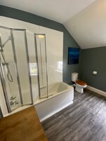 A modern bathroom with a glass-enclosed shower, a freestanding bathtub, and a toilet.