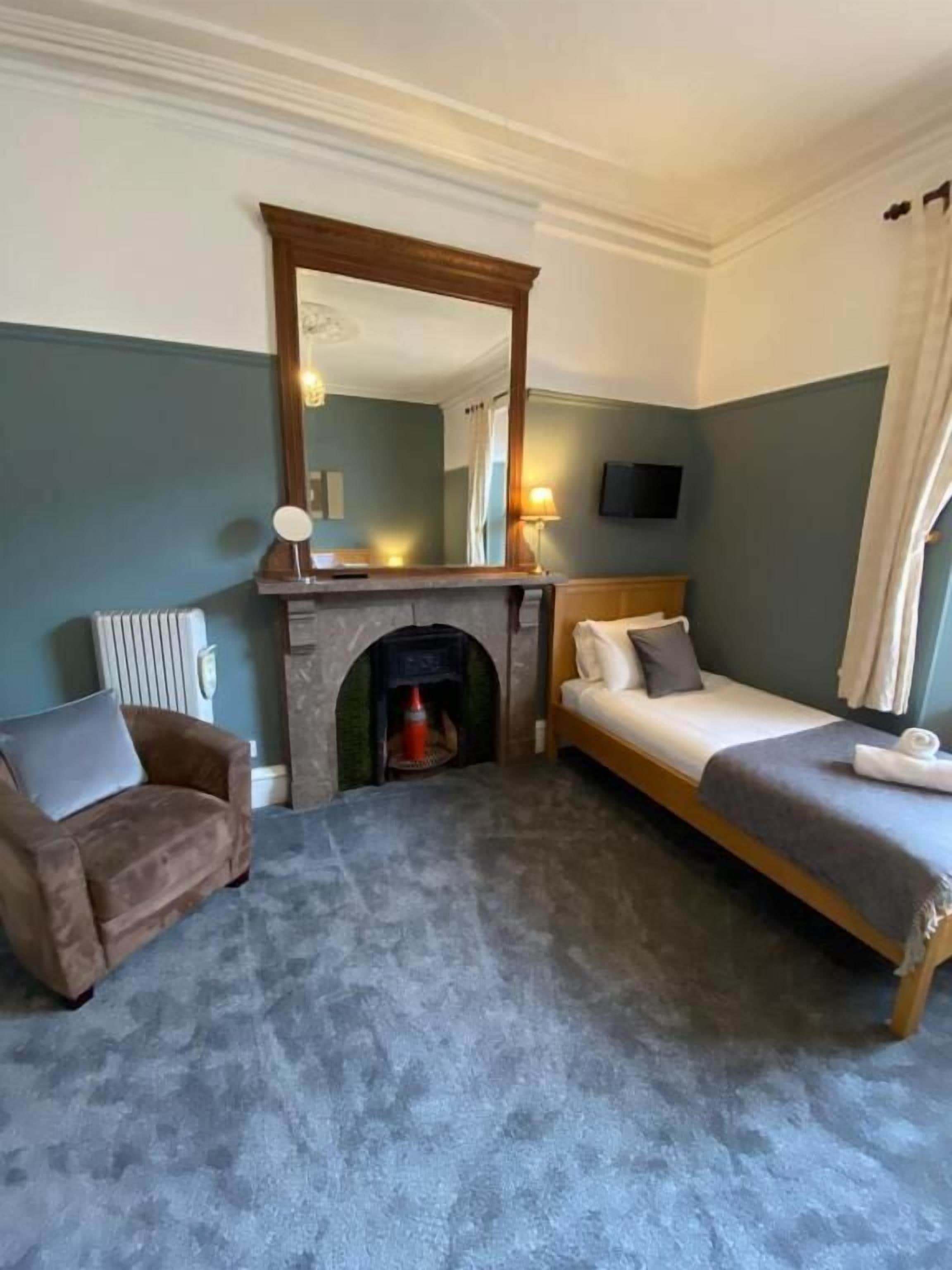 Una habitación de hotel con chimenea, un sofá, una cama y un televisor.