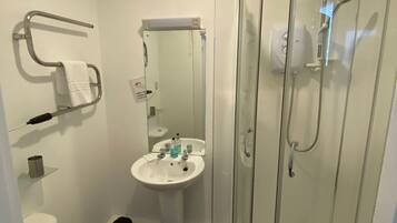 A bathroom with a toilet, sink, and glass shower enclosure.