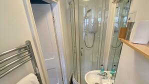 Uma casa de banho compacta com duche, sanita e lavatório.