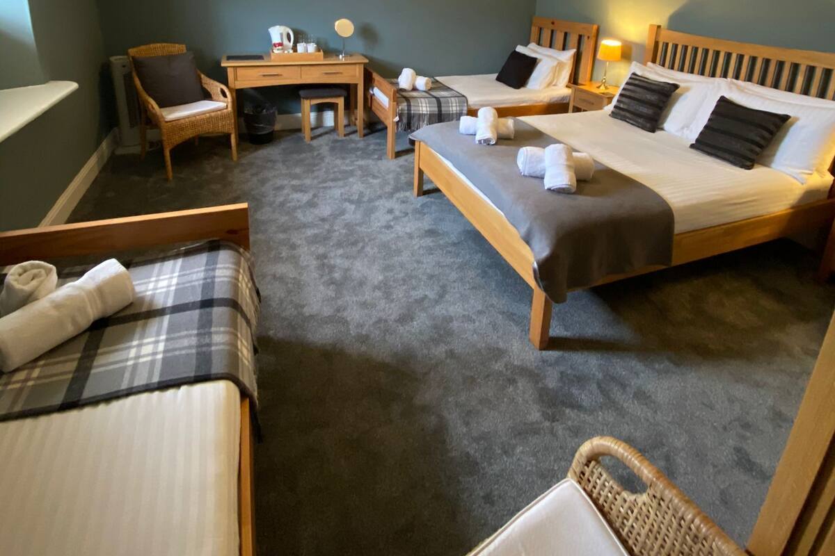 A hotel room with two beds, a desk, a chair, and a small table.