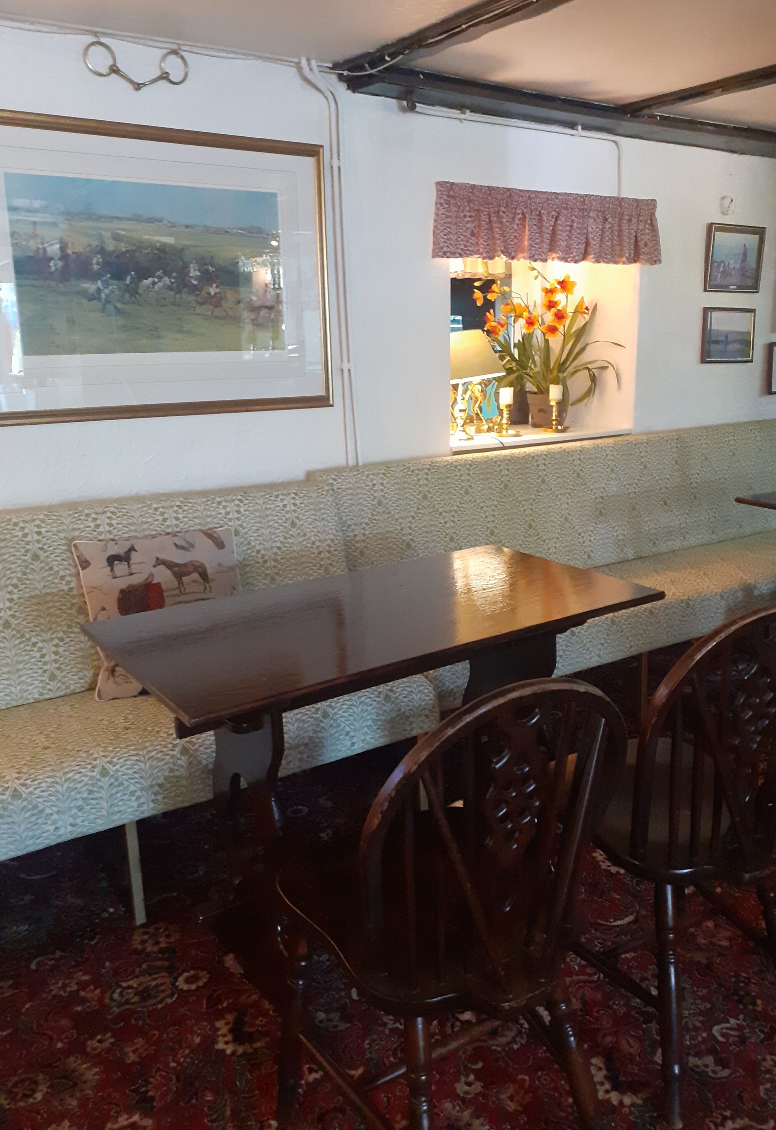 A dining area with a wooden table, chairs, a bench, and a window with a view of a field.