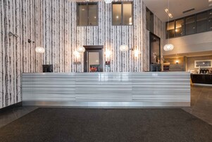 A modern reception area with a patterned wall, a reception desk, and pendant lighting.