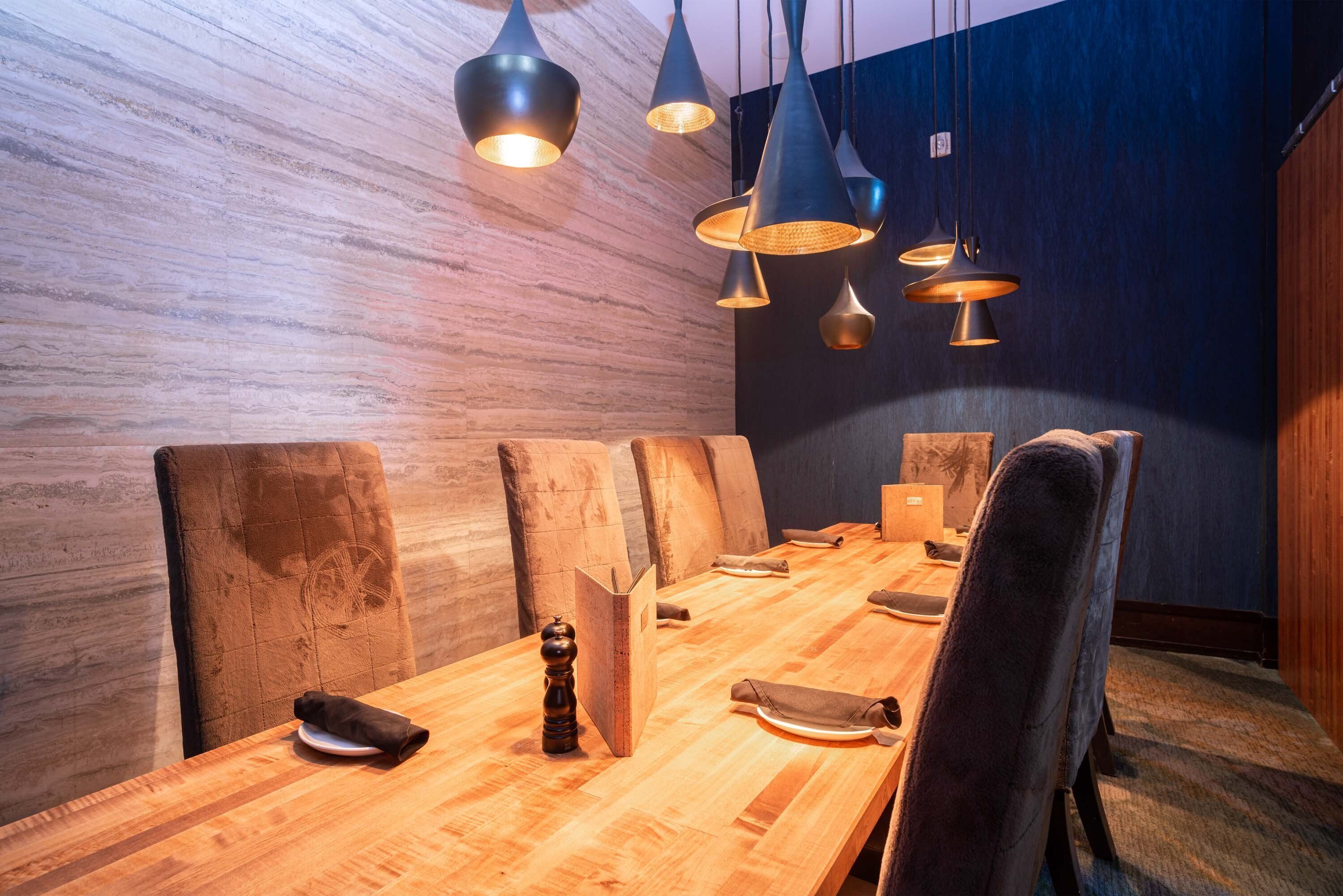 Un salón de conferencias con una larga mesa de madera, varias sillas e iluminación colgante.