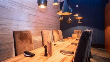 Un salón de conferencias con una larga mesa de madera, varias sillas e iluminación colgante.