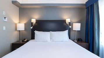 Une chambre d’hôtel avec un grand lit, deux tables de chevet avec des lampes, un téléphone et une horloge.