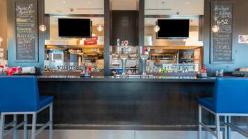 A modern bar area with a counter, bar stools, and a menu board.