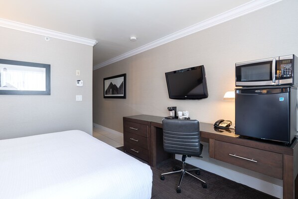 A hotel room with a bed, a desk with a chair, a television, a microwave, and a refrigerator. - Sandman Signature Edmonton South Hotel (Edmonton)