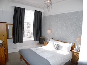 Une chambre bien rangée, avec un lit, des tables de chevet, une chaise et une armoire.