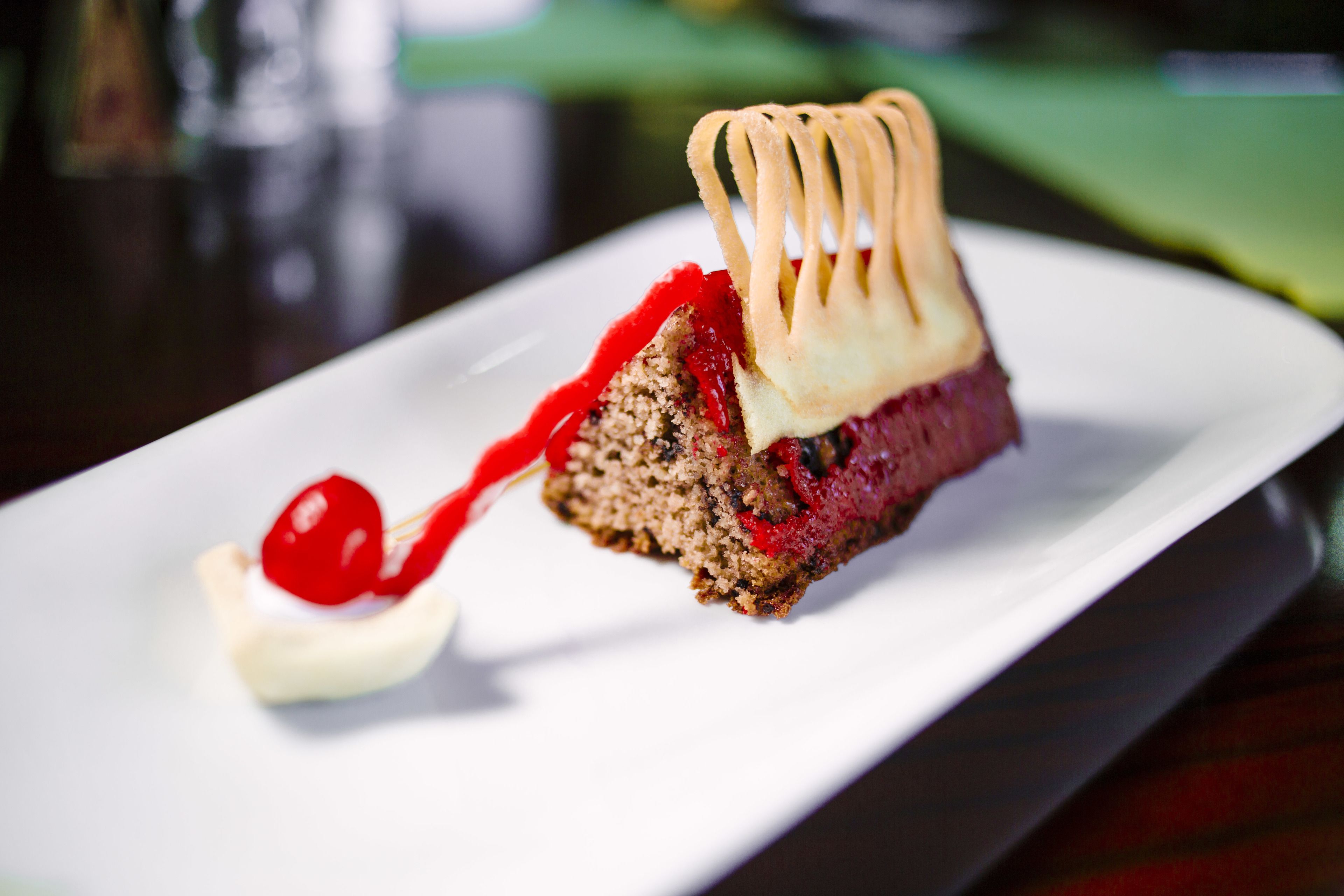 A dessert on a white plate with a cherry on a stick.