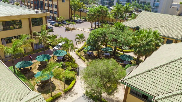 A courtyard with outdoor seating, palm trees, and a parking area. - Boma Inn Nairobi (Nairobi)